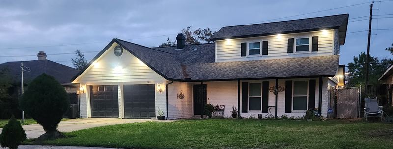 A home with the power on at dusk, backed by a standby generator